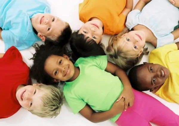 Group of children lying on the floor in a circular formation, dressed in brightly colored clothes.